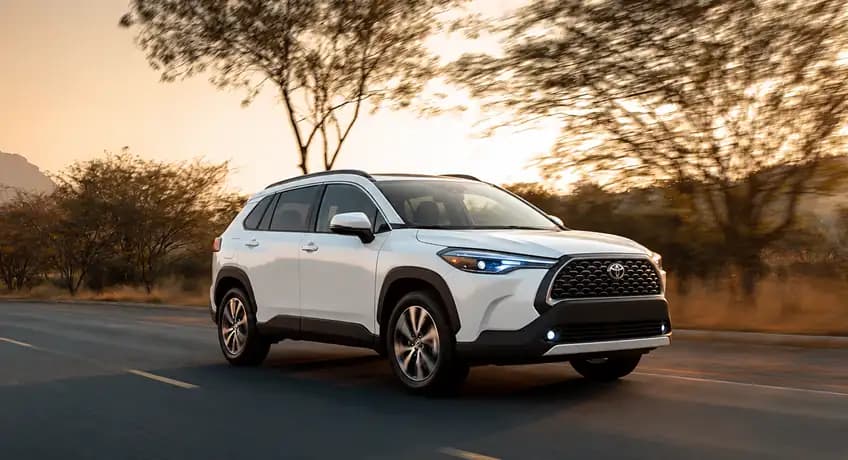 2025 Toyota Corolla Cross driving on a tree-lined road